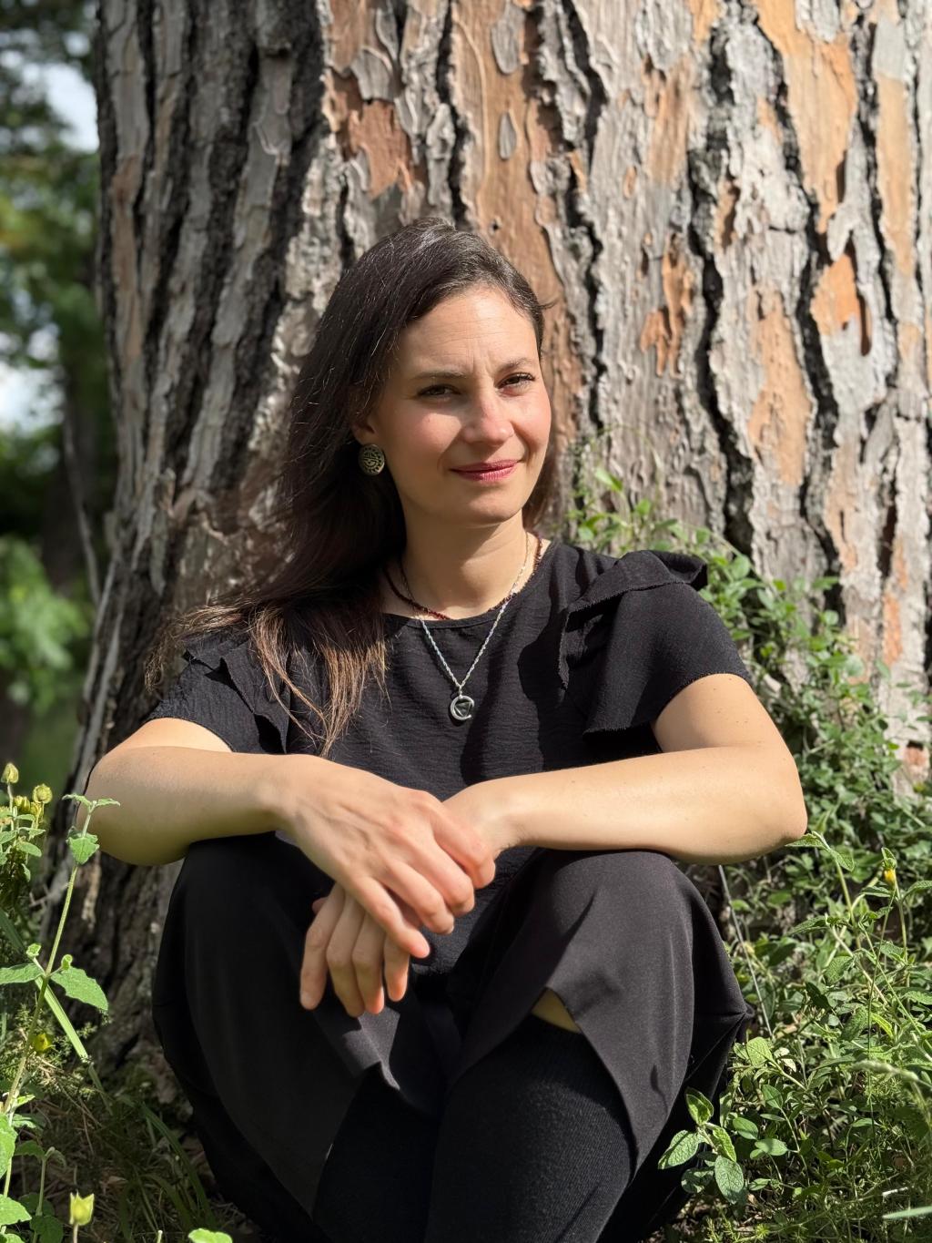 Chiara Piazza, partecipante di medium art experience appoggiata ad un albero, sorridendo